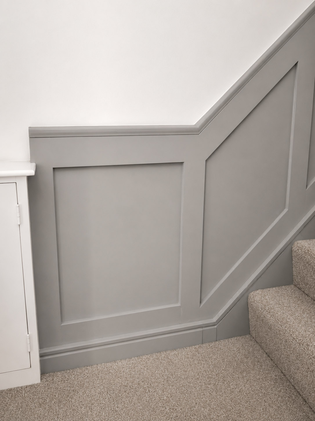 Grey bespoke wall panelling fitted around the lower staircase and hallway by Elite