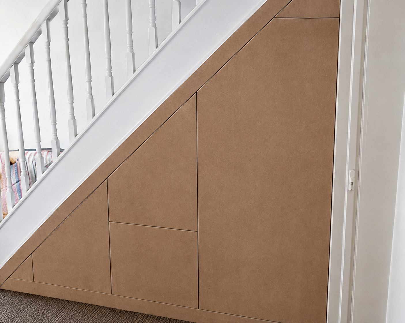 Made-to-measure understairs storage frontage fitted neatly to follow the staircase angle by Elite